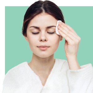 A woman wiping her face after an organic lift facial.